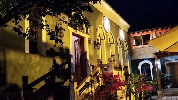 Um edifício com escadaria, porta e varanda.