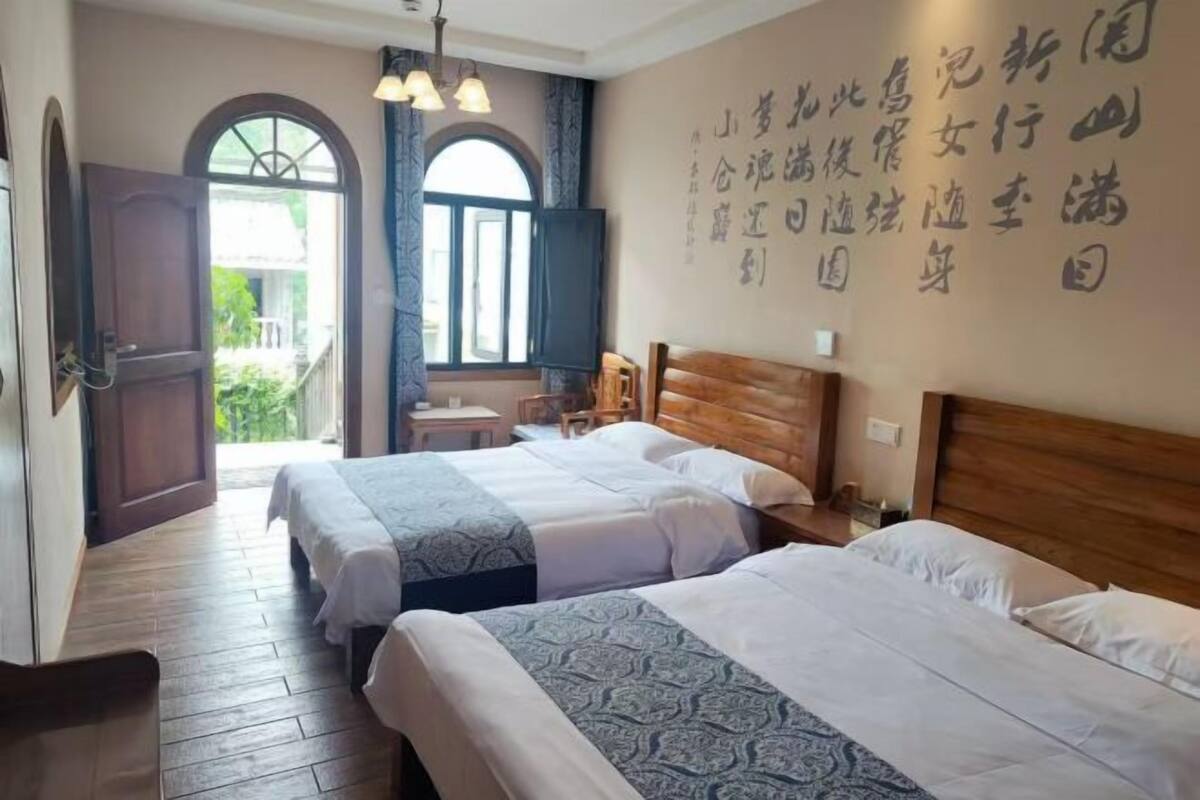 A hotel room with two beds, a TV, a wooden headboard, and a wall with Chinese characters.