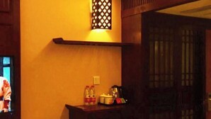 Quarto com escrivaninha de madeira, prateleira na parede, luminária de parede acesa e um sinal vermelho indicando 'WIFI'.