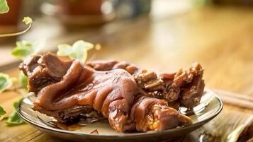 Um prato com um pedaço de carne sobre uma mesa de madeira.