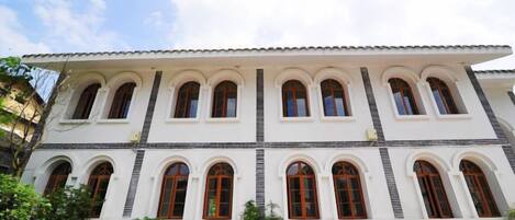A multi-story building with a white facade and multiple arched windows.