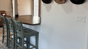 Un espace repas doté d’un plafond en bois, d’un luminaire, d’un porte-chapeaux fixé au mur et d’une table à manger avec des chaises.