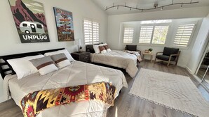 Une chambre d’hôtel avec deux lits, une grande fenêtre, un tapis et des œuvres d’art mural.