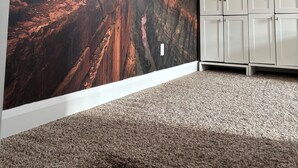 Une pièce avec un grand mur décoré d’une fresque représentant un canyon, des meubles blancs et un sol recouvert de moquette.