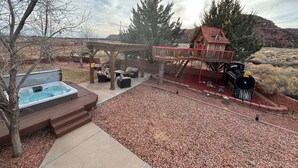 Un jardin avec un jacuzzi, du mobilier de jardin, une terrasse en bois et un petit train.