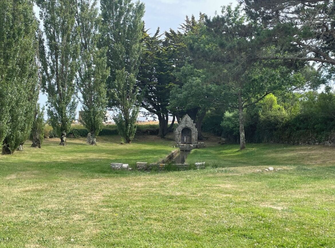 Un parc paisible avec un monument en pierre entouré d’arbres.