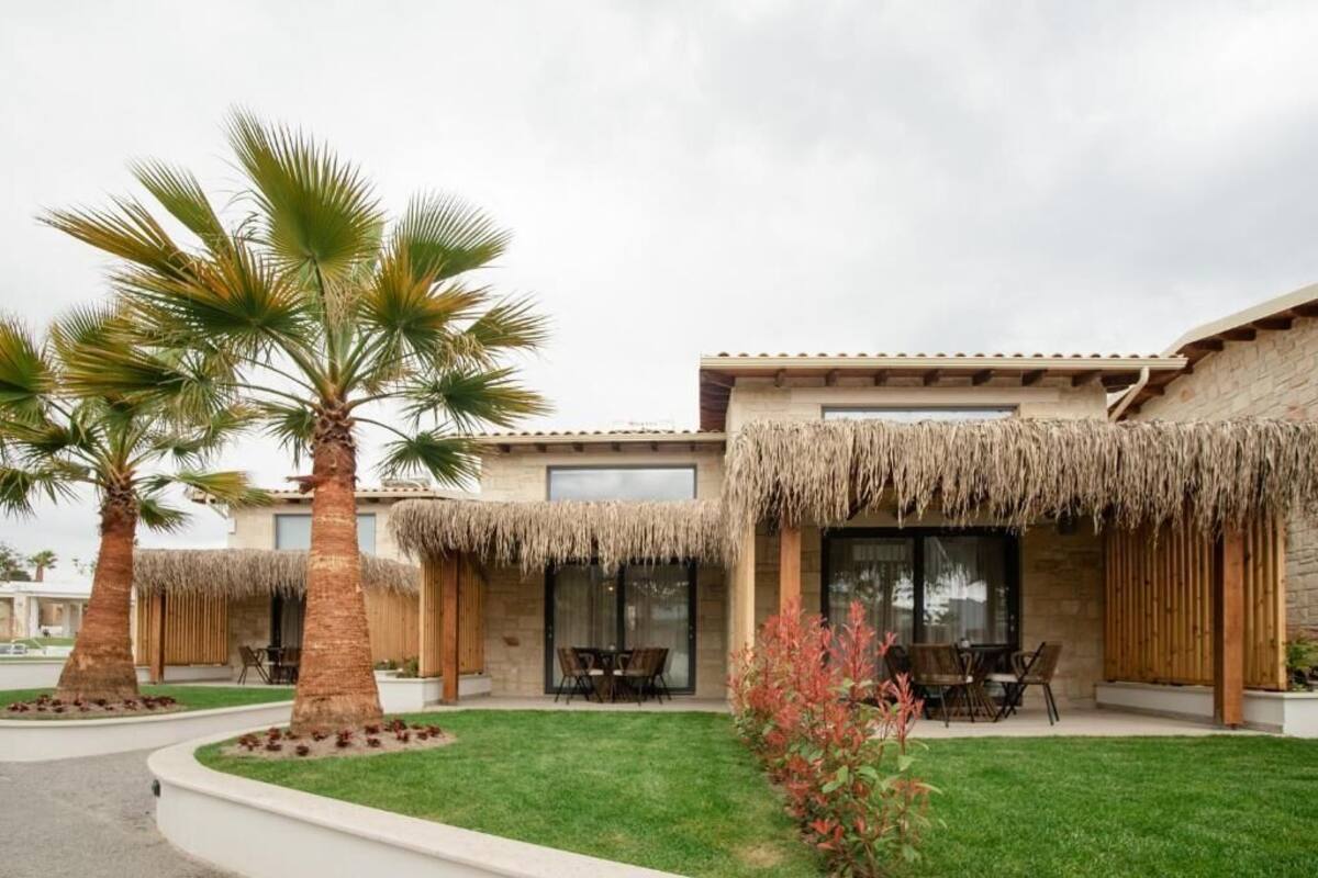 Una casa moderna con patio, palmeras y césped bien cuidado.