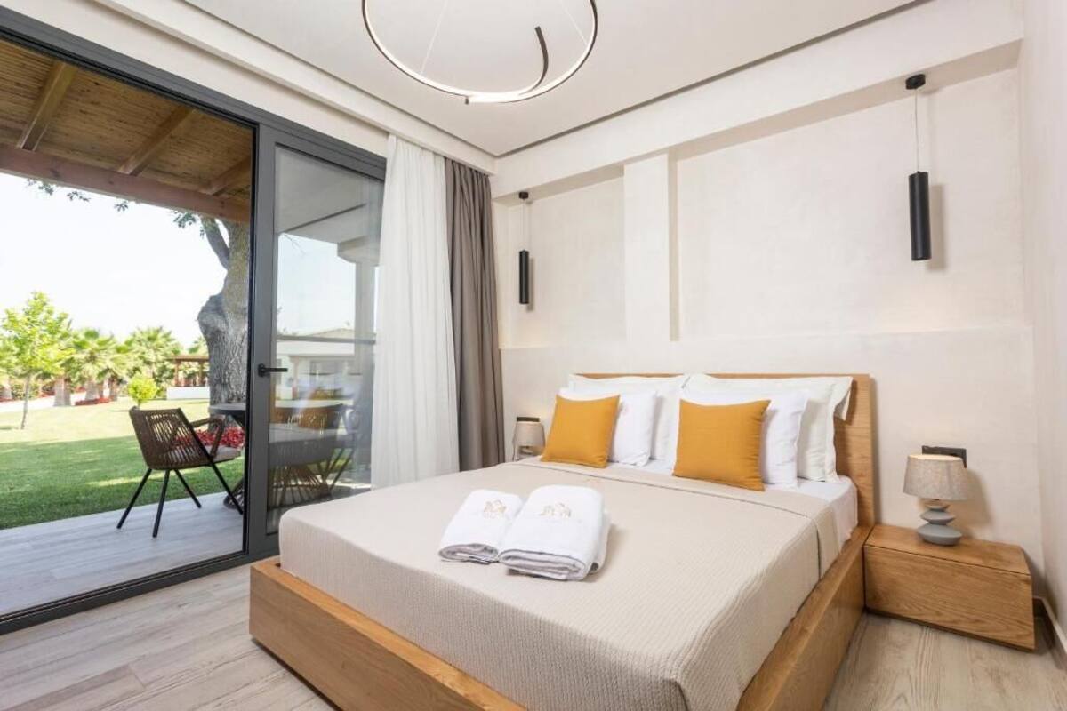 Un dormitorio moderno con una cama grande, una mesita de noche, una lámpara y un ventanal corredero que da a un balcón.