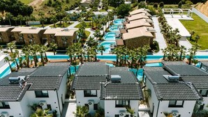 A resort with multiple buildings, a swimming pool area, and palm trees. - Kallithea Village (Kassandra)