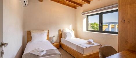 Un dormitorio con dos camas de madera, un escritorio de madera y una ventana con vistas al exterior.