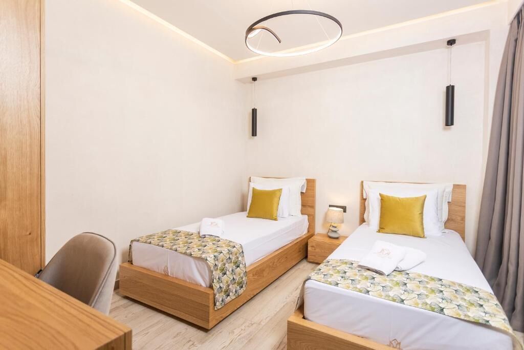 Una habitación de hotel con dos camas individuales, cabeceros de madera, un escritorio y una silla.