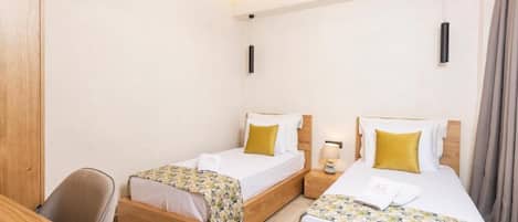 Une chambre d’hôtel avec deux lits simples, des têtes de lit en bois, un bureau et une chaise.