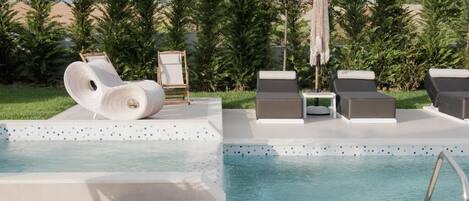 A poolside area with lounge chairs, a pool, and a pergola with a hanging plant.