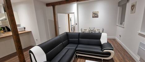 A modern living room with a black sectional sofa, a white coffee table, and a yellow rug.