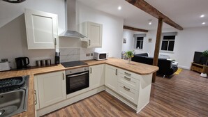 A modern kitchen with white cabinetry, a built-in oven, and a microwave. - Delightful New Period Conversion (Burnley)