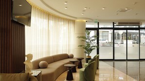 A modern lobby with a curved sofa, round tables, and a large window with a view of the street. - Tress Hotel (Istanbul)