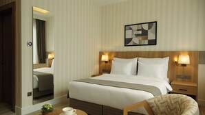 A hotel room with a large bed, bedside lamps, a wooden headboard, a small table with a cup and saucer, and a chair. - Tress Hotel (Istanbul)