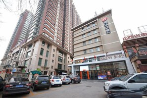A multi-story building with a ground-level commercial space, several parked cars, and a clear sky. - Jinjiang Inn Select (Taiyuan Pingyang Road) (Taiyuan)