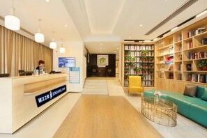 Un espace d’accueil comprenant un bureau en bois, un comptoir de réception et une bibliothèque remplie de livres.