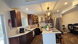 Uma cozinha moderna com armários de madeira escura, uma ilha central e uma área de refeições com mesa e cadeiras.