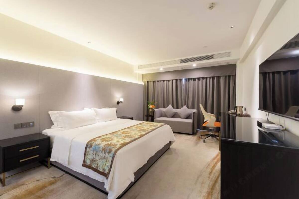 Une chambre d’hôtel moderne équipée d’un grand lit, d’un bureau, d’une chaise et d’un téléviseur.