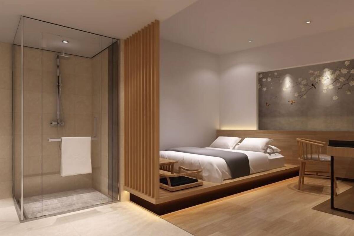 Une chambre à coucher moderne avec une douche en verre, un lit doté d’une structure en bois et un bureau fixé au mur.