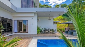 A modern two-story house with a swimming pool, outdoor dining area, and a brick oven. - Lapas House (Garavito)