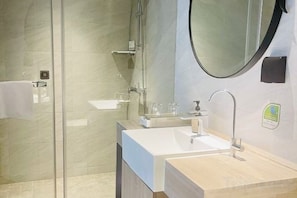A modern bathroom with a glass shower enclosure, a sink with a mirror, and a towel rack. - Fairyland Premium Hotel (Kunming Tuodong Sports Center Tangzixiang Metro Station) (Kunming)