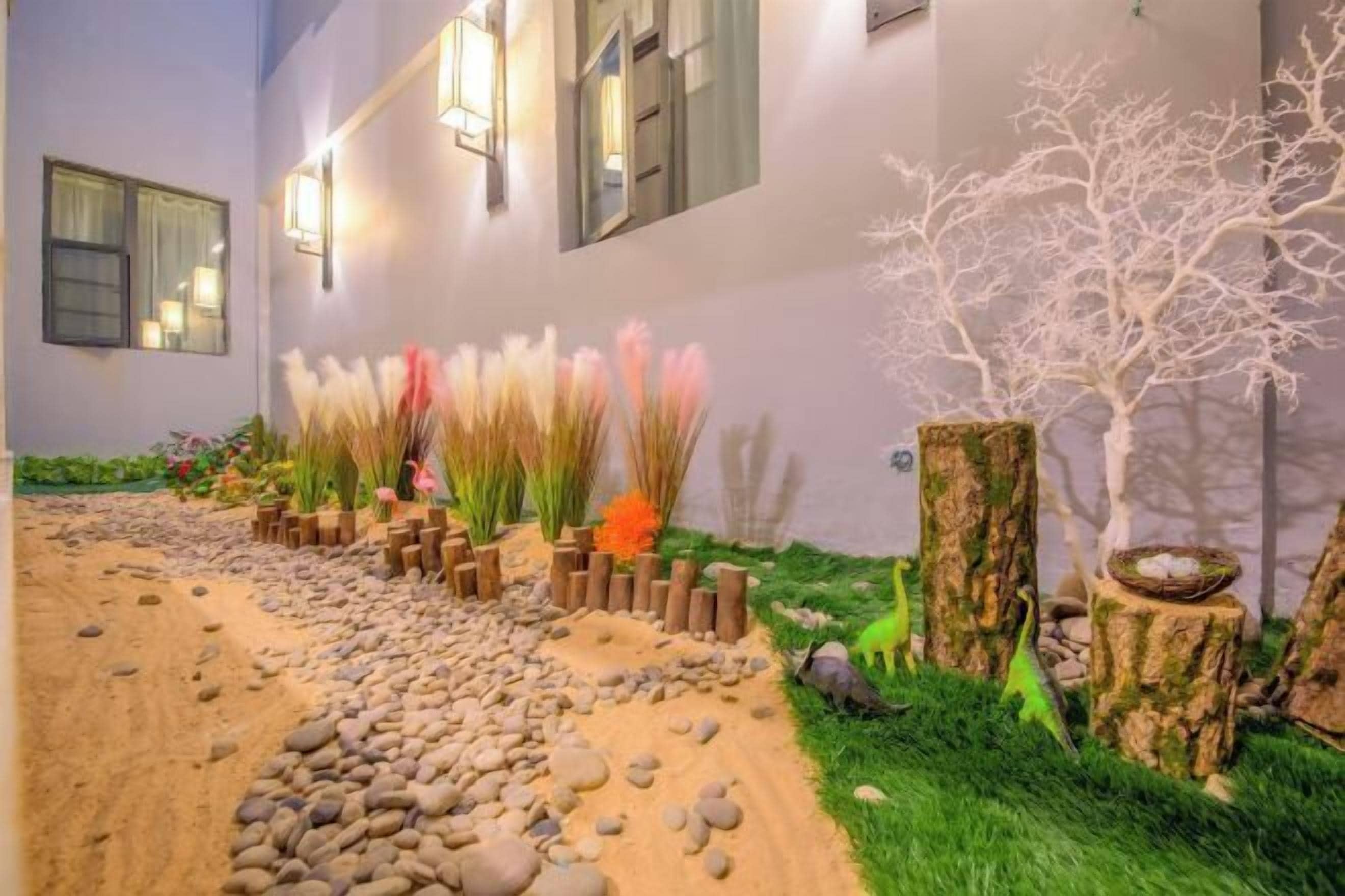 Een aangelegde pad met rotsen, beplanting en een witte boomsculptuur.