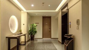 Um corredor moderno com uma mesa de recepção, uma planta em vaso, um telefone e uma lixeira.