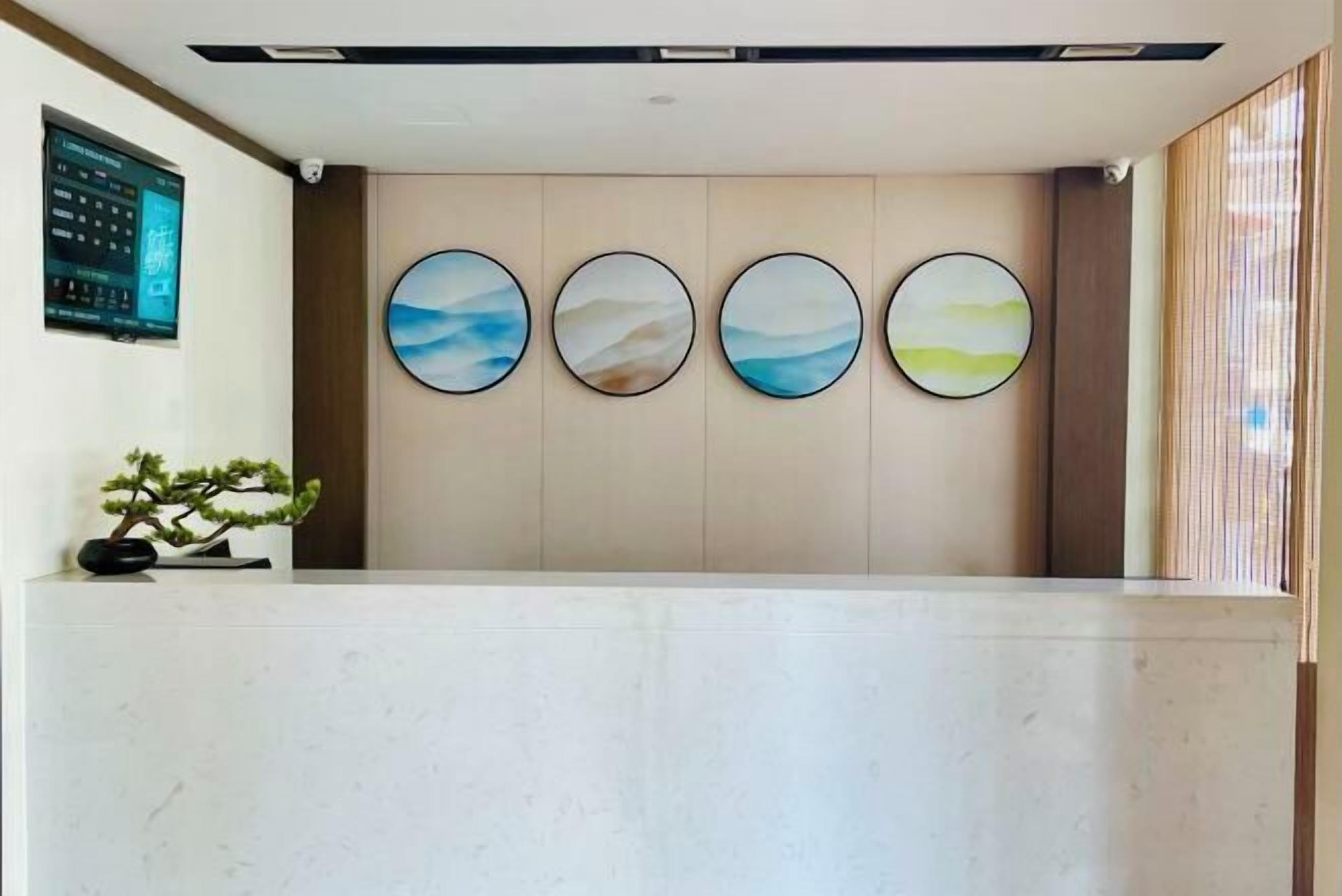 A reception area with a marble counter, four circular wall art pieces, and a digital display on the left.