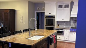 Een moderne keuken met een groot eiland, een inbouwoven, magnetron en roestvrijstalen apparatuur.