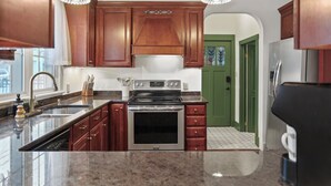 A kitchen with wooden cabinets, stainless steel appliances, granite countertops, and pendant lighting.