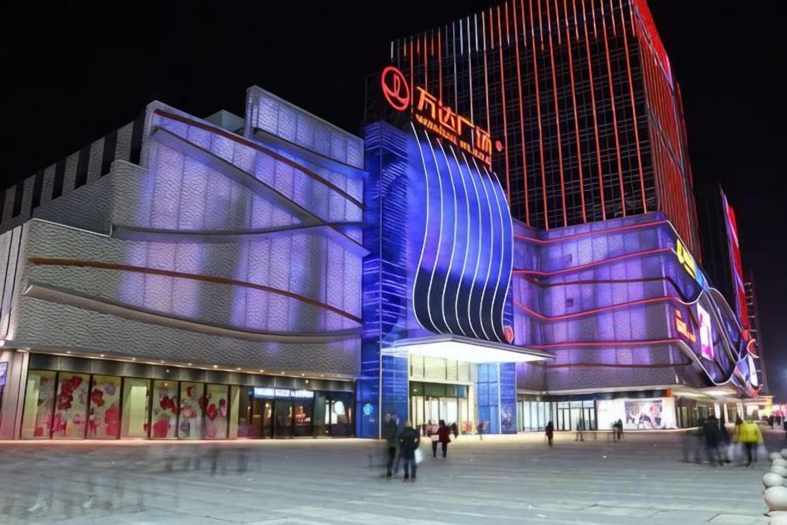Un edificio moderno con una fachada curva llamativa y señalización iluminada.