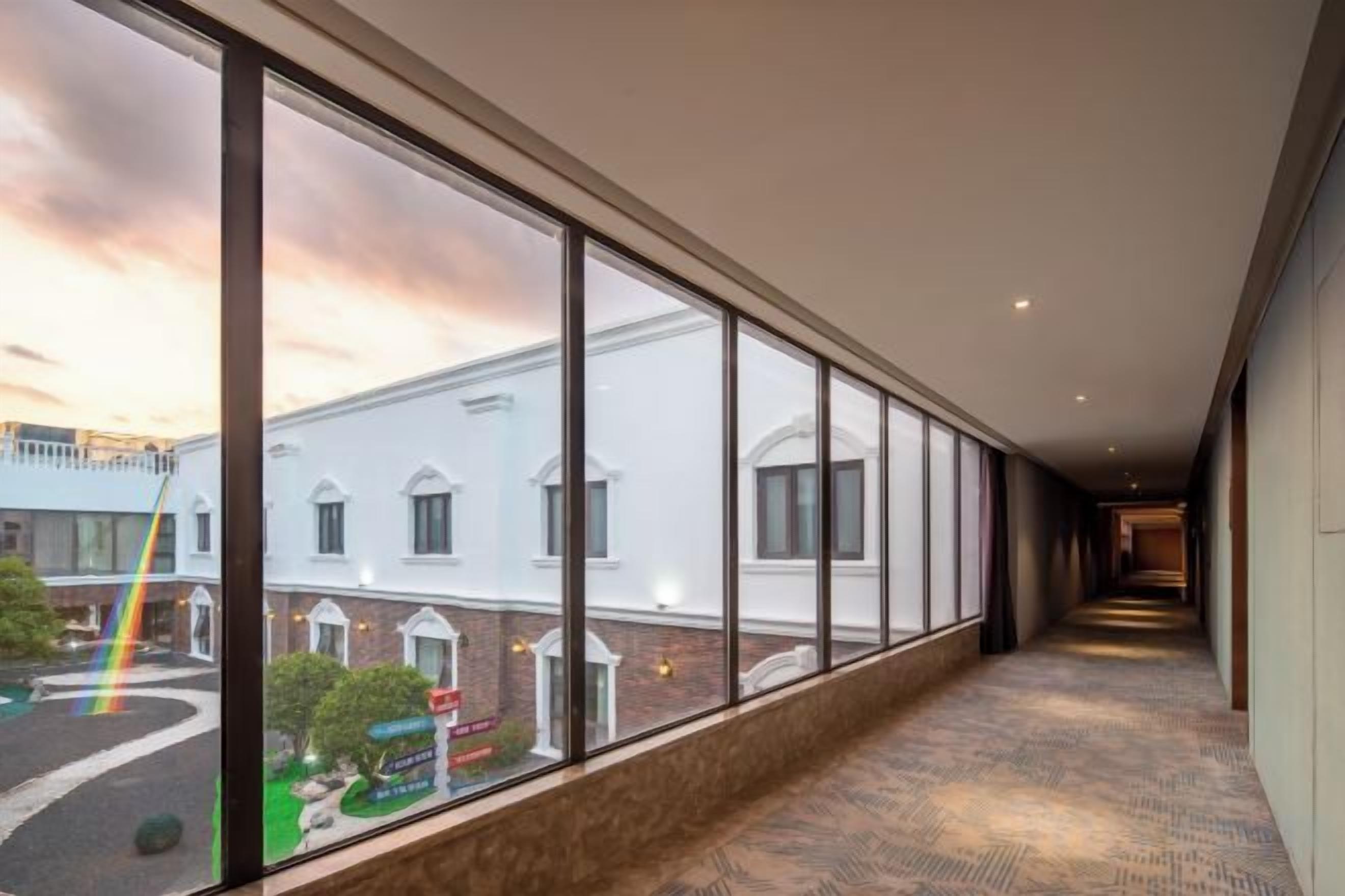 A corridor with large windows, a carpeted floor, and a view of a building with a brick facade.