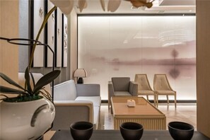 Una sala de estar moderna con un sofá, dos sillones, una mesita de centro y una planta en maceta.