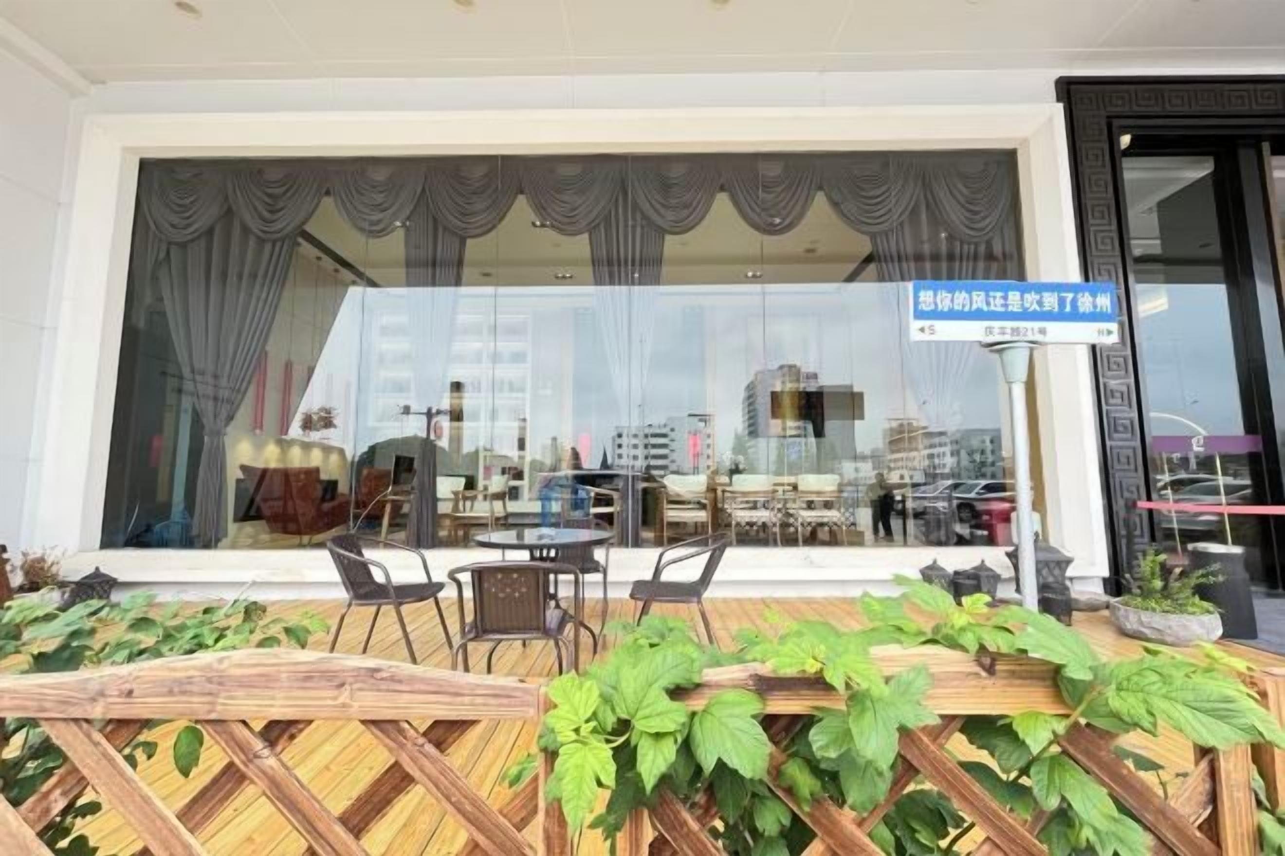 A hotel room with a large window, a wooden table with chairs, and a view of the cityscape.