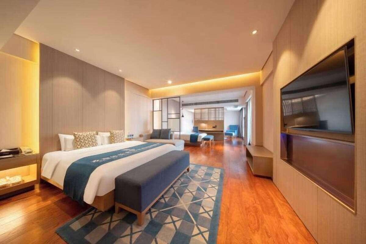 Une chambre d’hôtel moderne équipée d’un grand lit, d’un bureau, d’une télévision et d’un coin salon.
