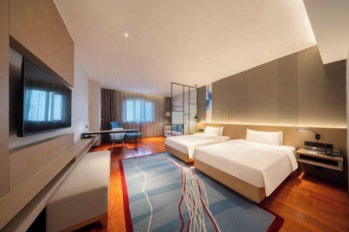 Une chambre d’hôtel moderne dotée d’une grande télévision à écran plat, de deux lits, d’un bureau et d’un coin salon.