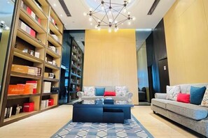 Un hall d’hôtel avec un canapé, une table basse et une bibliothèque.
