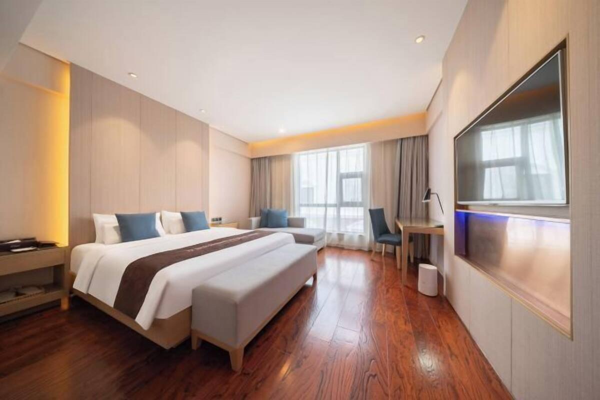 Une chambre d’hôtel moderne, dotée d’un grand lit, d’un bureau et d’une télévision.