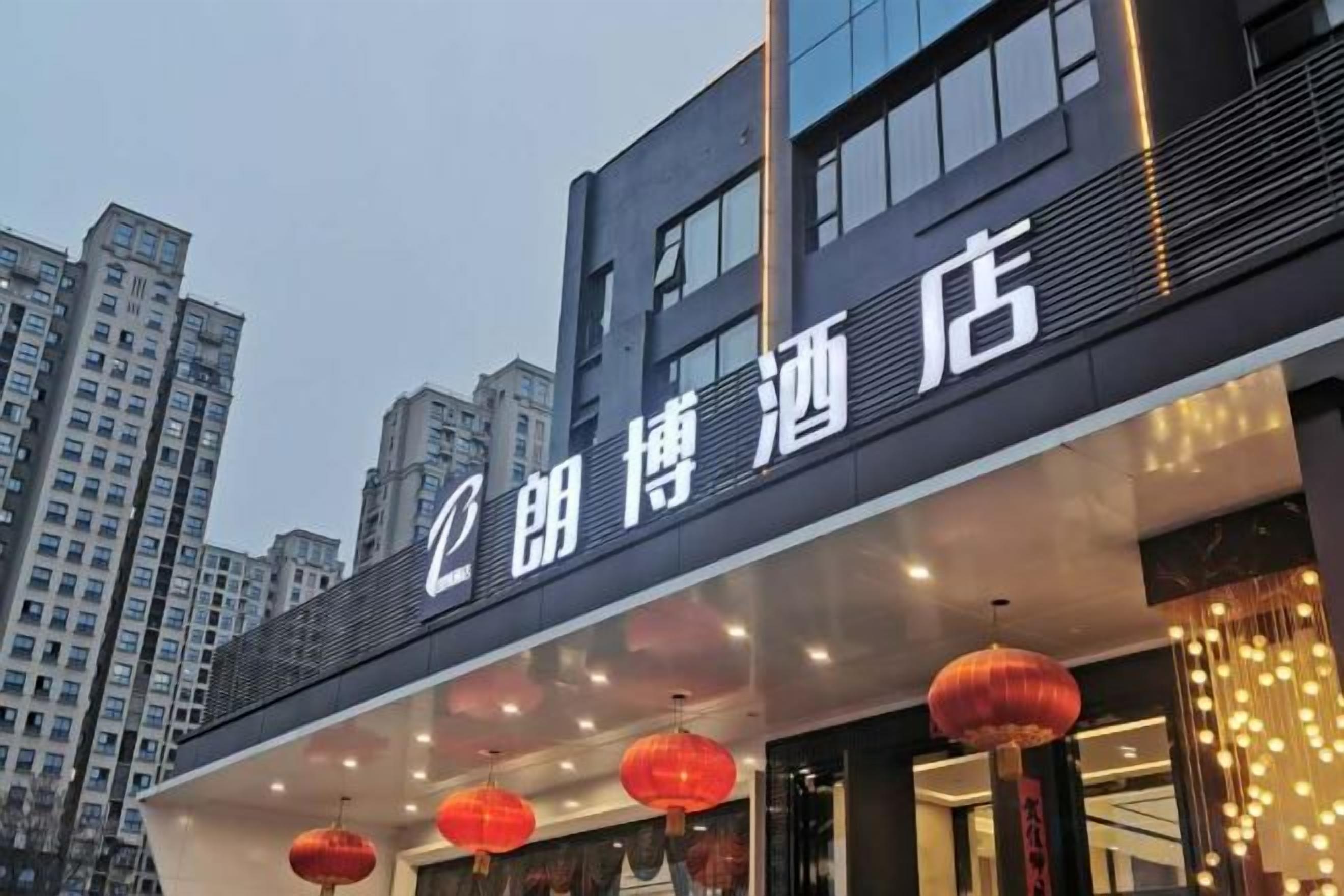A hotel with a modern facade, illuminated signage, and red lanterns.