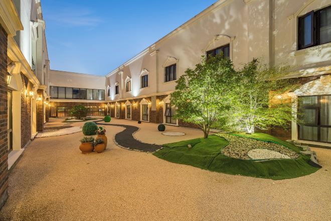 A courtyard with a gravel path, a small tree, and potted plants.