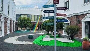 A courtyard with directional signs, a rainbow, and a green area.