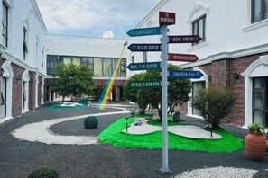 Ein Innenhof mit Hinweisschildern, einem Regenbogen und einer Grünfläche.