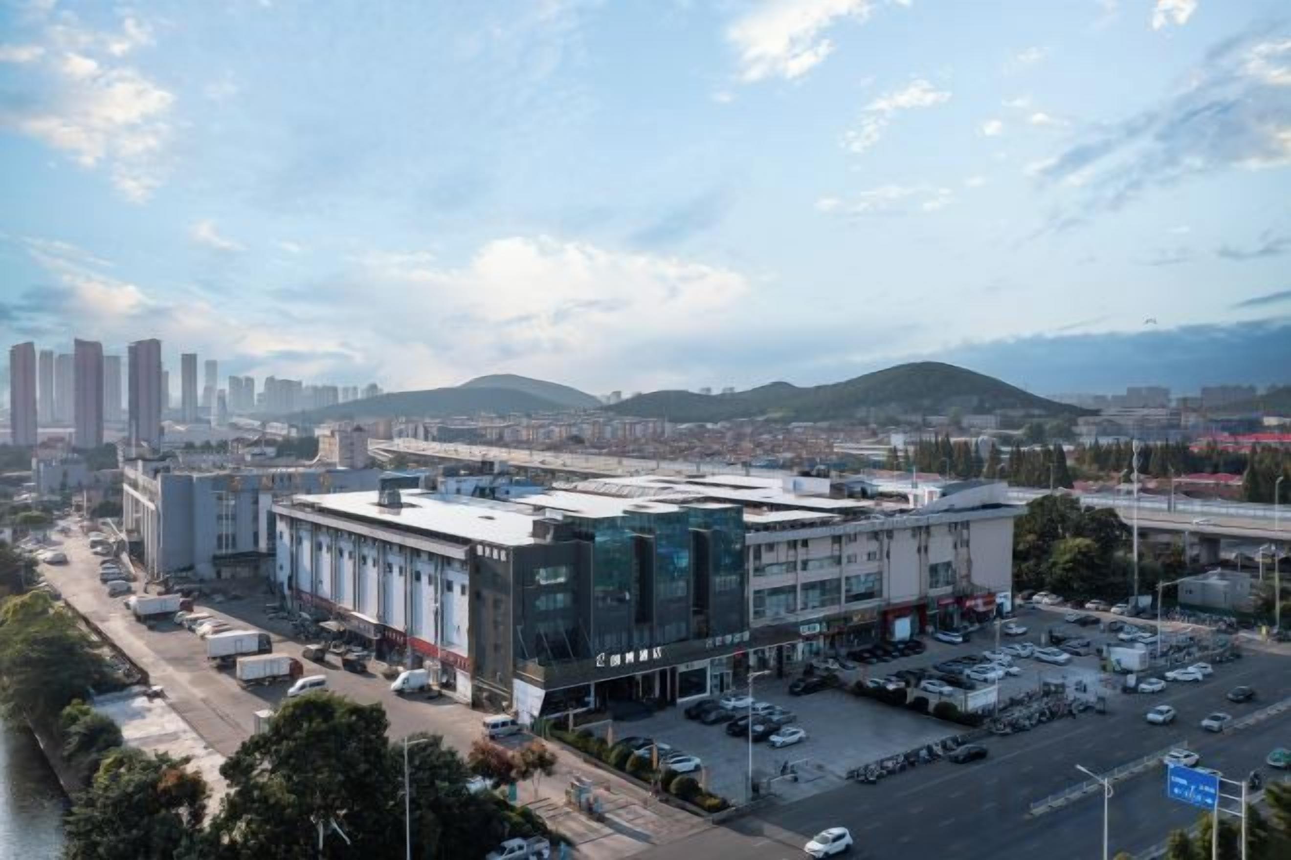 A large industrial building with multiple parking lots and a river in the foreground.