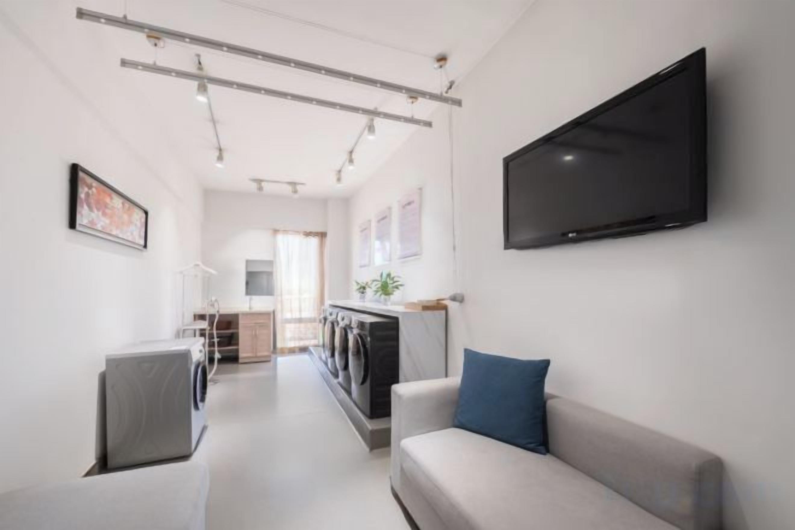 Una sala de estar moderna con un televisor de pantalla plana, un sofá y una lavadora.