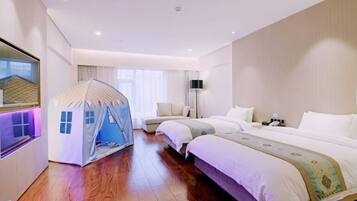 A hotel room with a large bed, a small tent-like structure, a bedside table, and a flat-screen TV.