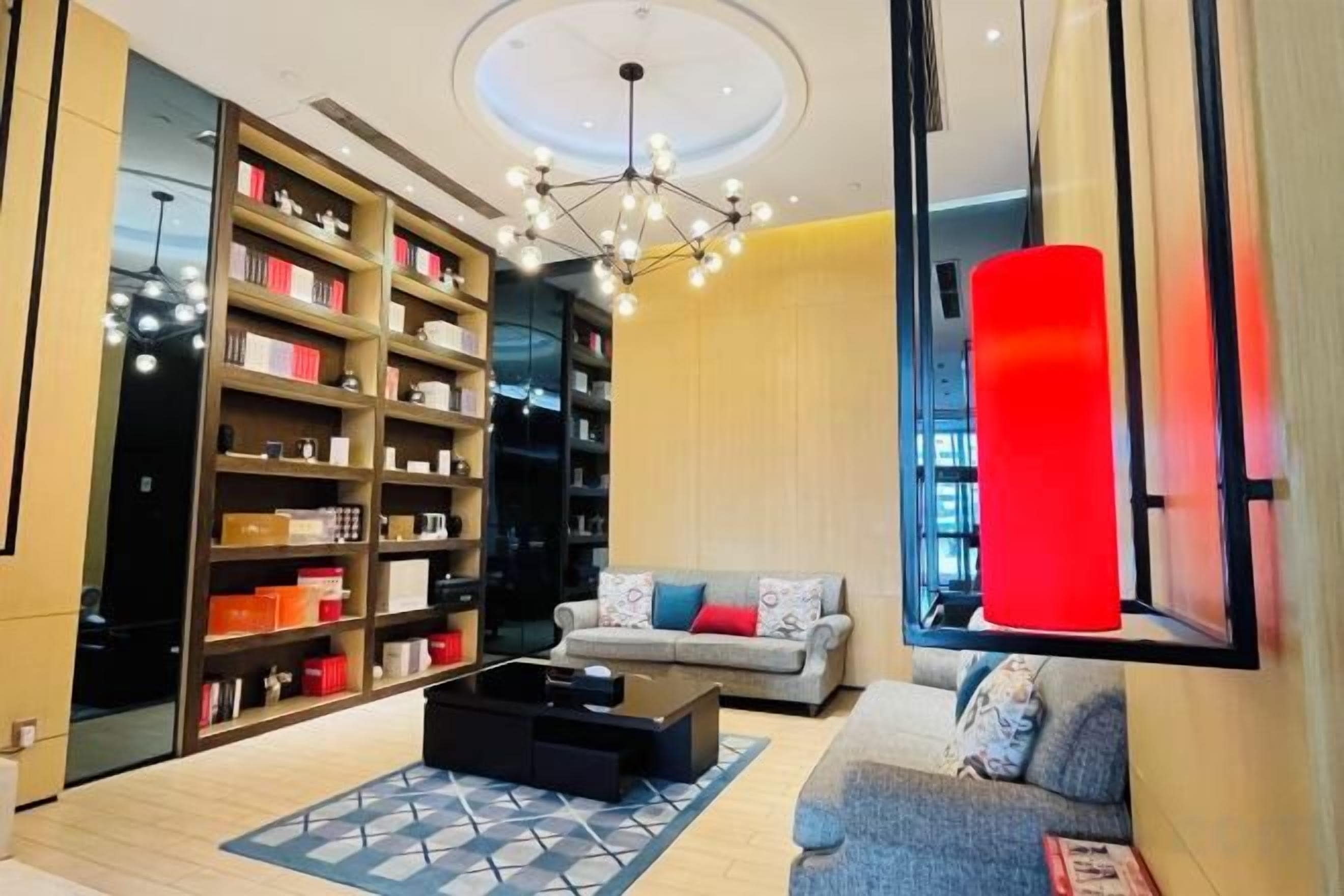 A modern living room with a large bookshelf, a sofa, a coffee table, and a unique red accent wall.