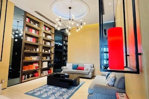 A modern living room with a large bookshelf, a sofa, a coffee table, and a unique red accent wall.